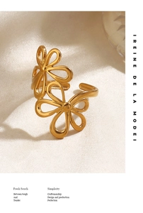 Detail of gold floral open ring on linen fabric with elegant shadow and brand text