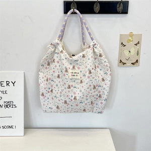 Detail of white embossed canvas tote with purple woven handles and cute bear pattern