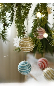 Detailed view of luxury threaded pearl Christmas ball hanging on pine branch with gold glitter