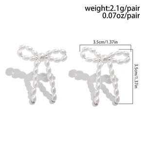 Detailed view of elegant white faux pearl bow earrings with silver-toned tassel accents