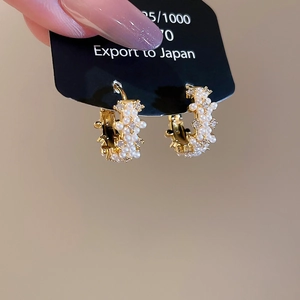Detailed macro view of 14K gold plated C-shaped earrings with pearls and crystals