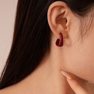 Boucles d'oreilles minimalistes en émail rouge foncé en forme de U portées par un mannequin