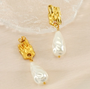 Détail de boucles d'oreilles vintage en or martelé avec grandes perles baroques blanches
