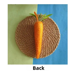 Detailed back view of artificial orange Easter carrot with green leaves on a straw mat