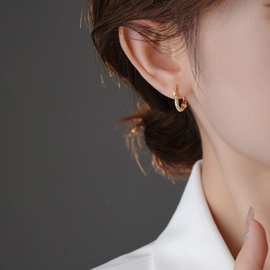 Close-up of a gold textured heart hoop earring on model with irregular surface detail