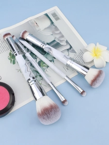 Detailed view of four marble-patterned makeup brushes with brown-white gradient bristles