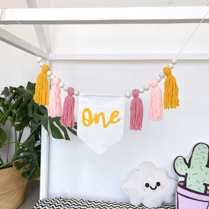 Detail of wooden beads and colorful tassels on a 'One' first birthday party banner