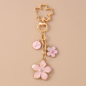 Detail of pink enamel cherry blossom keychain with golden letter Y charm on plain background