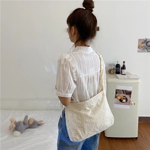 Daisy floral tote bag with pleated shoulder strap shown on a model in a cozy setting