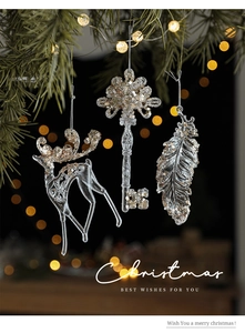 Close-up of clear acrylic reindeer and snowflake ornaments with silver glitter on Christmas tree