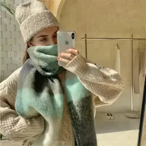Detail showing the green and grey plaid scarf paired with a light coffee knit beanie