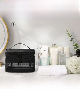 Detail view of black double-layer mesh wash bag with top handle on a clean counter