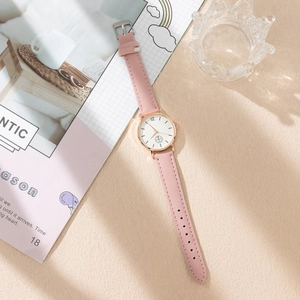 Detailed shot of rose gold quartz watch with a light pink matte leather strap on a desk