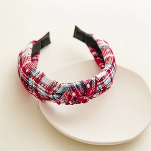 Detail of red and white checkered fabric headband with white embroidered stars and top knot