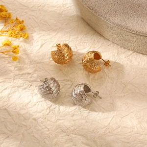 Textured C-shaped 18K gold and silver stainless steel earrings on a beige background