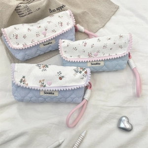 Detailed set of floral fabric pouches with pink pom-pom trim and quilted heart patterns