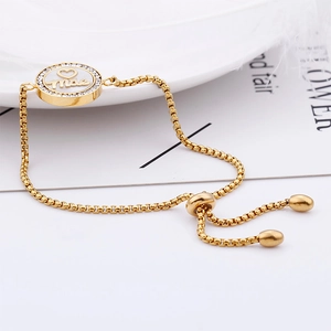 Detail of gold adjustable bracelet with sparkling diamond-set 'mae' letter pendant