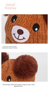 Detail of warm brown knit baby hat featuring cute bear embroidery and fluffy twin pom-poms