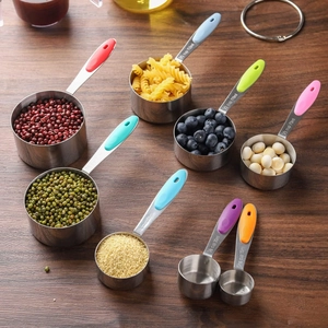 8-piece stainless steel measuring cups with colorful silicone handles on wood surface