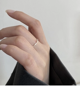 Anello in argento martellato irregolare minimalista su dito femminile con trama metallica