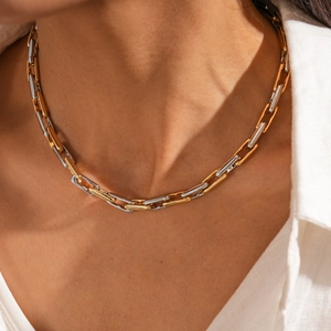 Close-up of gold and silver mixed chain necklace worn over a classic white shirt