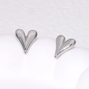 Macro shot of silver heart stud earrings with a high-polish mirror finish surface
