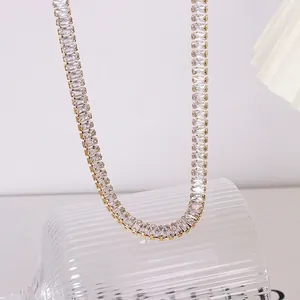 Elegante collana tennis dorata con zirconi rettangolari su una bottiglia di vetro