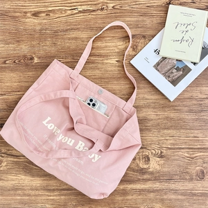 Detail of pink canvas tote interior pocket with a smartphone inside on wooden desk