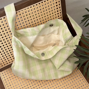 Close-up of green checkered canvas tote bag showing magnetic clasp and zipper pocket