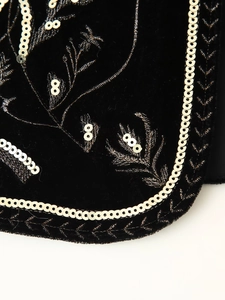 Detail of floral embroidery and sequin trim on black velvet street fashion vest