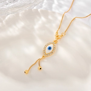 Detail of evil eye pendant with gold chain and zircon stones on a white ceramic plate