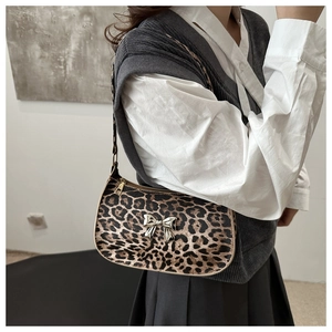 Detail of leopard print baguette bag with a silver metal bow accent and zipper closure