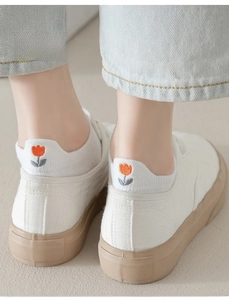 Detail of white cotton socks with colorful tulip embroidery and canvas sneakers