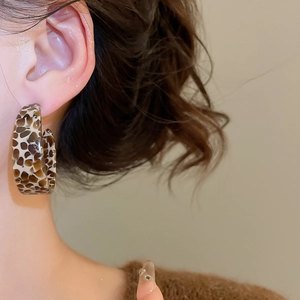 Close-up of tortoise shell pattern C-shape resin hoop earring worn by a model