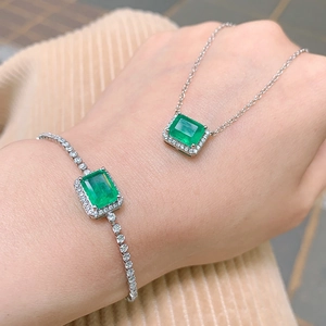 Close-up of emerald-cut green gemstone necklace and bracelet jewelry set on model