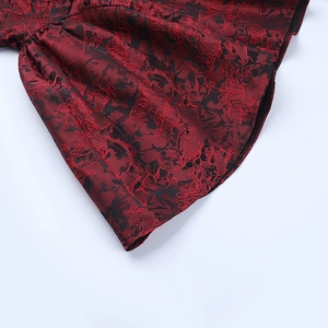 Detailed view of red and black floral jacquard fabric with elegant pleated texture