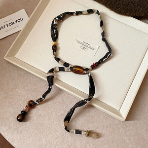 Macro detail of French retro fabric necklace with wooden beads and amber resin on beige tray