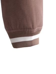 Dettaglio di tessuto twill marrone con polsino elastico a costine a righe bianche sulla giacca