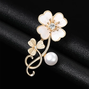 Macro detail of elegant clover flower brooch with pearl and shell inlay on black leather