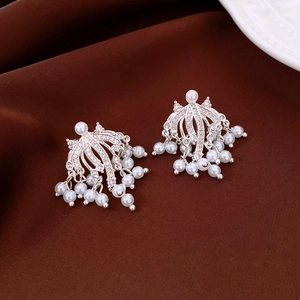 Detail view of silver tassel earrings with pearls and rhinestones on dark velvet background