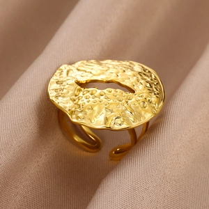 Macro view of gold-tone irregular textured ring with cutout on champagne silk fabric