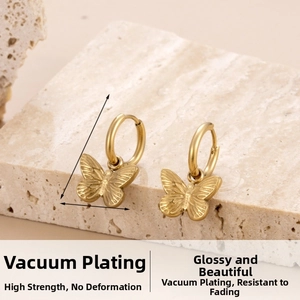 Close-up of gold butterfly pendant earrings on a minimalist natural stone background