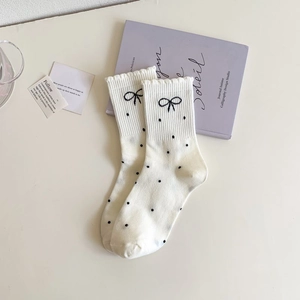 Detail of white crew socks featuring black polka dots and delicate bow embroidery