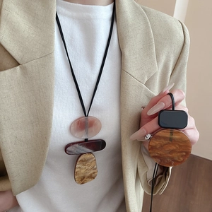 Detail of amber resin geometric pendant necklace with black cord on beige blazer