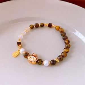 Dettaglio del bracciale in occhio di tigre e perle con ciondolo dorato Ping An