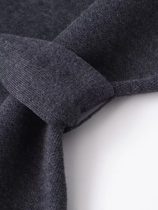 Dettaglio del tessuto a maglia grigio scuro che mostra la trama fine e le cuciture ai bordi