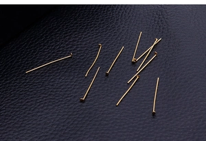 Macro view of gold stainless steel flat head pins on textured black leather surface