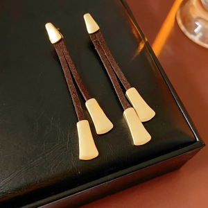 Detail of vintage brown suede leather fringe earrings with irregular gold metal charms
