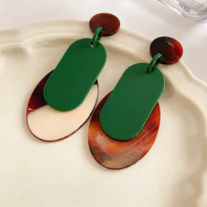 Vintage green resin geometric earrings with marble pattern on a ceramic dish