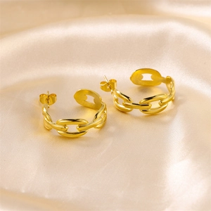 Macro shot of gold-plated chain link hoop earrings on silk fabric background